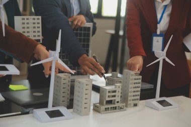 Tablete yakın çekim, Mühendisler tableti elleriyle işaret ediyorlar. Rüzgar ve güneş enerjisiyle yenilenebilir enerji kullanımını ortaklaşa tasarlamak için. Yenilenebilir enerji kullanma kavramı.