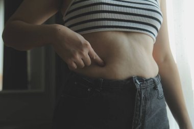 Kadın göbeği. Şişman kadın göbek yağlarını tutuyor. diyet yaşam tarzı konsepti karın kaslarını zayıflatmak ve sağlıklı mide kaslarını şekillendirmek için.