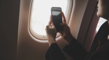 Sarışın kadın turist gelen bildirim netbook ile uçak koltuğunda oturan Smartphone cep telefonu ile kontrol. Genç işkadını paylaşmak medya telefonu dizüstü bilgisayar üzerinde uçak uçuş sırasında