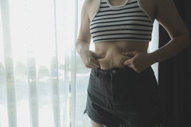 Kadın göbeği. Şişman kadın göbek yağlarını tutuyor. diyet yaşam tarzı konsepti karın kaslarını zayıflatmak ve sağlıklı mide kaslarını şekillendirmek için.