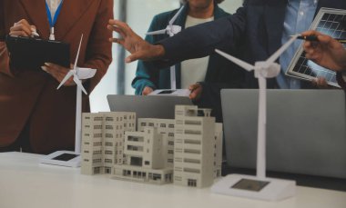 Tablete yakın çekim, Mühendisler tableti elleriyle işaret ediyorlar. Rüzgar ve güneş enerjisiyle yenilenebilir enerji kullanımını ortaklaşa tasarlamak için. Yenilenebilir enerji kullanma kavramı.