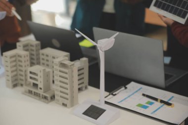 Tablete yakın çekim, Mühendisler tableti elleriyle işaret ediyorlar. Rüzgar ve güneş enerjisiyle yenilenebilir enerji kullanımını ortaklaşa tasarlamak için. Yenilenebilir enerji kullanma kavramı.