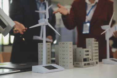 Tablete yakın çekim, Mühendisler tableti elleriyle işaret ediyorlar. Rüzgar ve güneş enerjisiyle yenilenebilir enerji kullanımını ortaklaşa tasarlamak için. Yenilenebilir enerji kullanma kavramı.