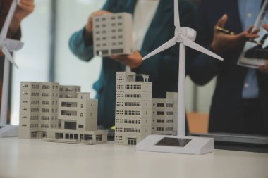 Tablete yakın çekim, Mühendisler tableti elleriyle işaret ediyorlar. Rüzgar ve güneş enerjisiyle yenilenebilir enerji kullanımını ortaklaşa tasarlamak için. Yenilenebilir enerji kullanma kavramı.