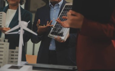Tablete yakın çekim, Mühendisler tableti elleriyle işaret ediyorlar. Rüzgar ve güneş enerjisiyle yenilenebilir enerji kullanımını ortaklaşa tasarlamak için. Yenilenebilir enerji kullanma kavramı.
