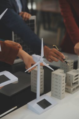 Tablete yakın çekim, Mühendisler tableti elleriyle işaret ediyorlar. Rüzgar ve güneş enerjisiyle yenilenebilir enerji kullanımını ortaklaşa tasarlamak için. Yenilenebilir enerji kullanma kavramı.