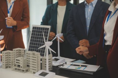 Tablete yakın çekim, Mühendisler tableti elleriyle işaret ediyorlar. Rüzgar ve güneş enerjisiyle yenilenebilir enerji kullanımını ortaklaşa tasarlamak için. Yenilenebilir enerji kullanma kavramı.