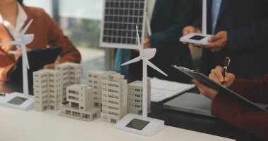 Tablete yakın çekim, Mühendisler tableti elleriyle işaret ediyorlar. Rüzgar ve güneş enerjisiyle yenilenebilir enerji kullanımını ortaklaşa tasarlamak için. Yenilenebilir enerji kullanma kavramı.