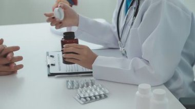Üniformalı genç erkek doktor hastasına hap veriyor.