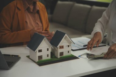 Discussion with a real estate agent, House model with agent and customer discussing for the contract to buy, get insurance or loan real estate or property.