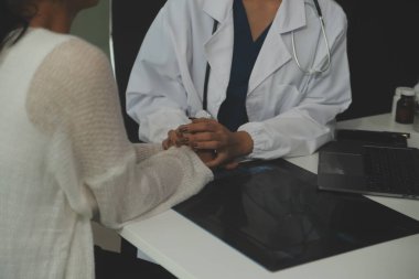Asyalı kadın doktor hastanedeki kadın hastaya umut veriyor ve onu cesaretlendiriyor. Gülümseyen doktor kadın hasta omzuna dokunuyor. Bakımı ve yardımı için. Desteklenen ve cesaretlendirilen