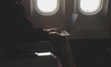 Sarışın kadın turist gelen bildirim netbook ile uçak koltuğunda oturan Smartphone cep telefonu ile kontrol. Genç işkadını paylaşmak medya telefonu dizüstü bilgisayar üzerinde uçak uçuş sırasında
