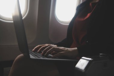 Sarışın kadın turist gelen bildirim netbook ile uçak koltuğunda oturan Smartphone cep telefonu ile kontrol. Genç işkadını paylaşmak medya telefonu dizüstü bilgisayar üzerinde uçak uçuş sırasında