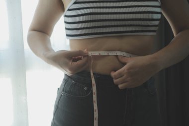 Kadın göbeği. Şişman kadın göbek yağlarını tutuyor. diyet yaşam tarzı konsepti karın kaslarını zayıflatmak ve sağlıklı mide kaslarını şekillendirmek için.