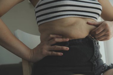 Kadın göbeği. Şişman kadın göbek yağlarını tutuyor. diyet yaşam tarzı konsepti karın kaslarını zayıflatmak ve sağlıklı mide kaslarını şekillendirmek için.