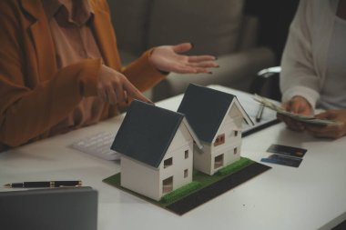 Discussion with a real estate agent, House model with agent and customer discussing for the contract to buy, get insurance or loan real estate or property.