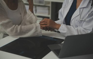 Asyalı kadın doktor hastanedeki kadın hastaya umut veriyor ve onu cesaretlendiriyor. Gülümseyen doktor kadın hasta omzuna dokunuyor. Bakımı ve yardımı için. Desteklenen ve cesaretlendirilen