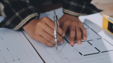 Planlarla çalışan ve yere çizim yapan bir adam..