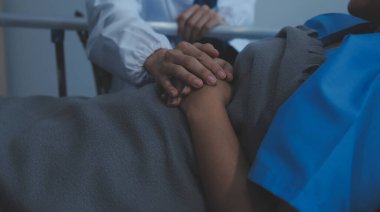 Kadın bir hemşirenin kıdemli hastasının elini tutarken çekilmiş bir fotoğrafı. Destek vermek için. Doktor yaşlı hastaya Alzheimer hastalığı konusunda yardım ediyor. Kadın bakıcı kıdemli adamın elini tutuyor.