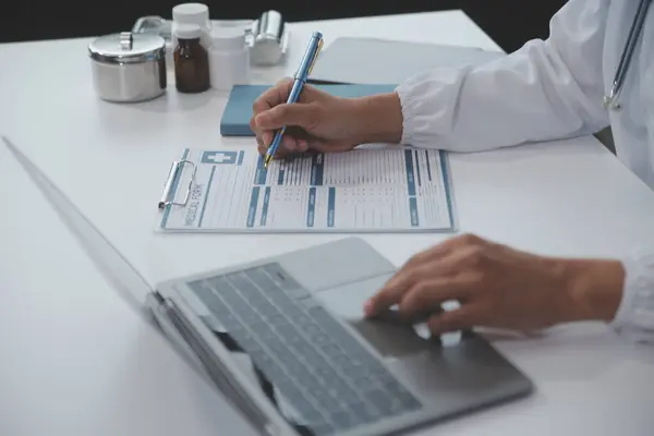 Önlüklü profesyonel ve odaklanmış Asyalı kadın bir doktor hastanede bilgisayarında tıbbi araştırmaları okuyor ve çalışıyor..