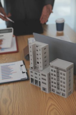 Emlak sektörünü dengelemek. Emlakçı ev tasarımını ve satın alma anlaşmasını görmek için ev tarzını anlatıyor. Modern ofiste ahşap ev.