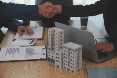 Emlak acentesi kontrat imzalandıktan sonra müşteriyle tokalaşıyor