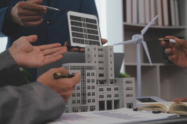 Mimarlar ve iş adamları, emlak sürdürülebilir yatırımları ve güneş enerjisi konut geliştirme projesi için zemin planı modifikasyonunu tartışıyor ve üzerinde kafa yoruyorlar.
