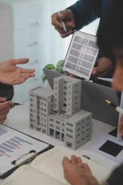Mimarlar ve iş adamları, emlak sürdürülebilir yatırımları ve güneş enerjisi konut geliştirme projesi için zemin planı modifikasyonunu tartışıyor ve üzerinde kafa yoruyorlar.