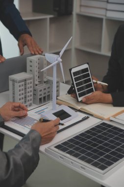 Mimarlar ve iş adamları, emlak sürdürülebilir yatırımları ve güneş enerjisi konut geliştirme projesi için zemin planı modifikasyonunu tartışıyor ve üzerinde kafa yoruyorlar.