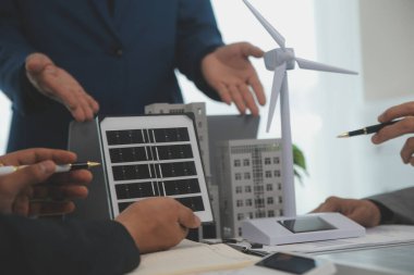 Mimarlar ve iş adamları, emlak sürdürülebilir yatırımları ve güneş enerjisi konut geliştirme projesi için zemin planı modifikasyonunu tartışıyor ve üzerinde kafa yoruyorlar.