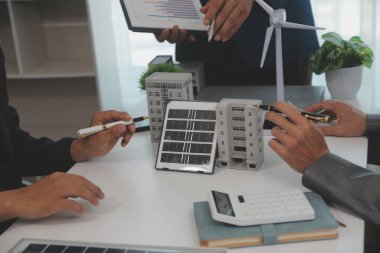 Mimarlar ve iş adamları, emlak sürdürülebilir yatırımları ve güneş enerjisi konut geliştirme projesi için zemin planı modifikasyonunu tartışıyor ve üzerinde kafa yoruyorlar.