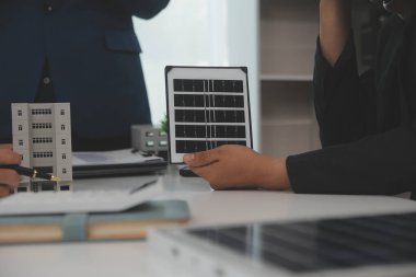 Mimarlar ve iş adamları, emlak sürdürülebilir yatırımları ve güneş enerjisi konut geliştirme projesi için zemin planı modifikasyonunu tartışıyor ve üzerinde kafa yoruyorlar.