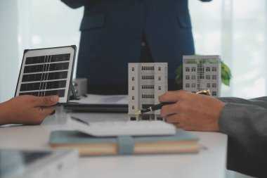 Mimarlar ve iş adamları, emlak sürdürülebilir yatırımları ve güneş enerjisi konut geliştirme projesi için zemin planı modifikasyonunu tartışıyor ve üzerinde kafa yoruyorlar.