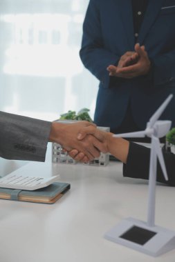 Kask ve yelek tutan inşaat işçileri el sıkışıyor. Emlak konsepti Mimar mühendis veya inşaatçı planlama ve başarılı toplantılarla el sıkışıyor