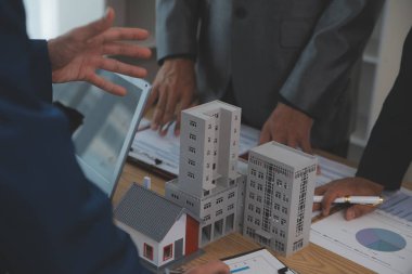 Emlak sektörünü dengelemek. Emlakçı ev tasarımını ve satın alma anlaşmasını görmek için ev tarzını anlatıyor. Modern ofiste ahşap ev.