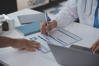 Önlüklü profesyonel ve odaklanmış Asyalı kadın bir doktor hastanede bilgisayarında tıbbi araştırmaları okuyor ve çalışıyor..