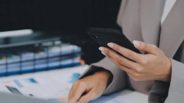 İş kadını ofiste cep telefonu ve dizüstü bilgisayar kullanıyor..