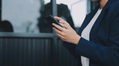 Ofisinde akıllı telefonu olan genç bir kadın.