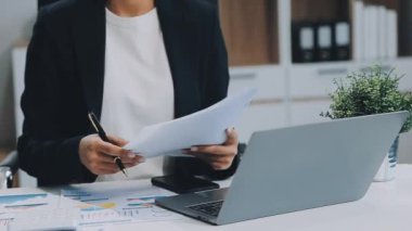 Ofiste hesap makinesi kullanan genç bir kadın.