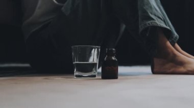 Genç adam masada oturuyor ve elinde bir bardak bira tutuyor.