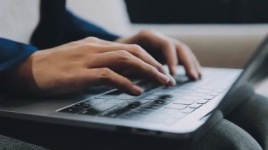 Ofisteki koltukta dizüstü bilgisayar kullanan bir adam.