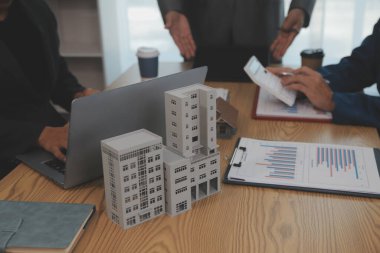 Emlak sektörünü dengelemek. Emlakçı ev tasarımını ve satın alma anlaşmasını görmek için ev tarzını anlatıyor. Modern ofiste ahşap ev.