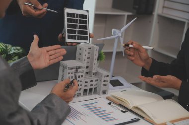 Mimarlar ve iş adamları, emlak sürdürülebilir yatırımları ve güneş enerjisi konut geliştirme projesi için zemin planı modifikasyonunu tartışıyor ve üzerinde kafa yoruyorlar.