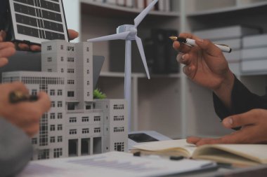 Mimarlar ve iş adamları, emlak sürdürülebilir yatırımları ve güneş enerjisi konut geliştirme projesi için zemin planı modifikasyonunu tartışıyor ve üzerinde kafa yoruyorlar.