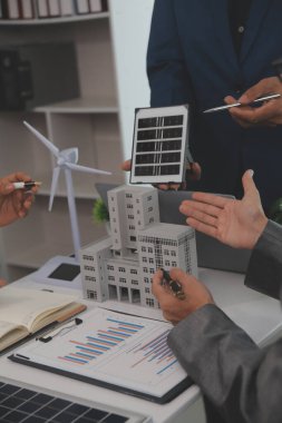 Mimarlar ve iş adamları, emlak sürdürülebilir yatırımları ve güneş enerjisi konut geliştirme projesi için zemin planı modifikasyonunu tartışıyor ve üzerinde kafa yoruyorlar.