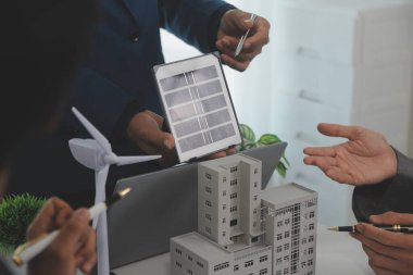 Mimarlar ve iş adamları, emlak sürdürülebilir yatırımları ve güneş enerjisi konut geliştirme projesi için zemin planı modifikasyonunu tartışıyor ve üzerinde kafa yoruyorlar.