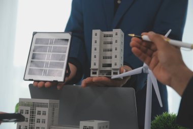 Mimarlar ve iş adamları, emlak sürdürülebilir yatırımları ve güneş enerjisi konut geliştirme projesi için zemin planı modifikasyonunu tartışıyor ve üzerinde kafa yoruyorlar.