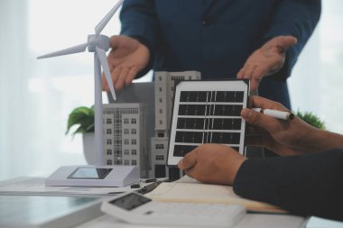 Mimarlar ve iş adamları, emlak sürdürülebilir yatırımları ve güneş enerjisi konut geliştirme projesi için zemin planı modifikasyonunu tartışıyor ve üzerinde kafa yoruyorlar.