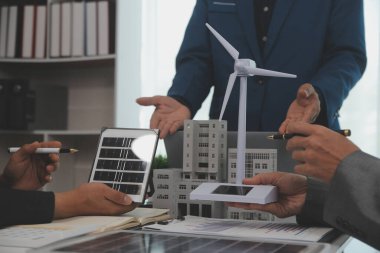Mimarlar ve iş adamları, emlak sürdürülebilir yatırımları ve güneş enerjisi konut geliştirme projesi için zemin planı modifikasyonunu tartışıyor ve üzerinde kafa yoruyorlar.