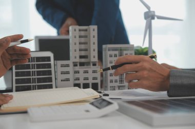 Mimarlar ve iş adamları, emlak sürdürülebilir yatırımları ve güneş enerjisi konut geliştirme projesi için zemin planı modifikasyonunu tartışıyor ve üzerinde kafa yoruyorlar.